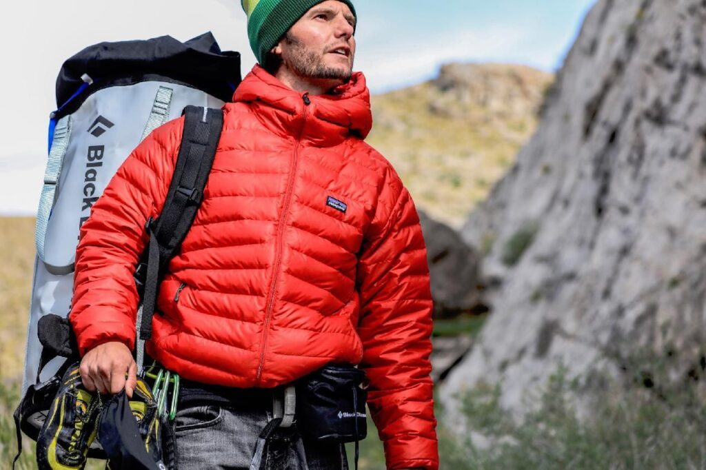 An intrepid explorer with a large backpack gazes into the distance, ready for a mountain adventure and mindful of heart health.