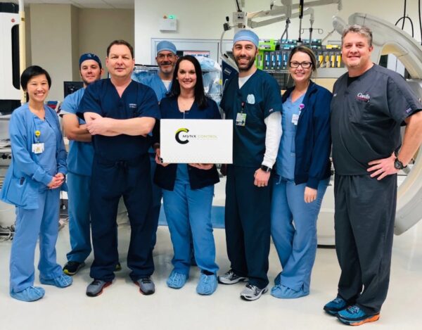 A group of happy looking CIS staff members poses with a box containing a Mynx Control closure device