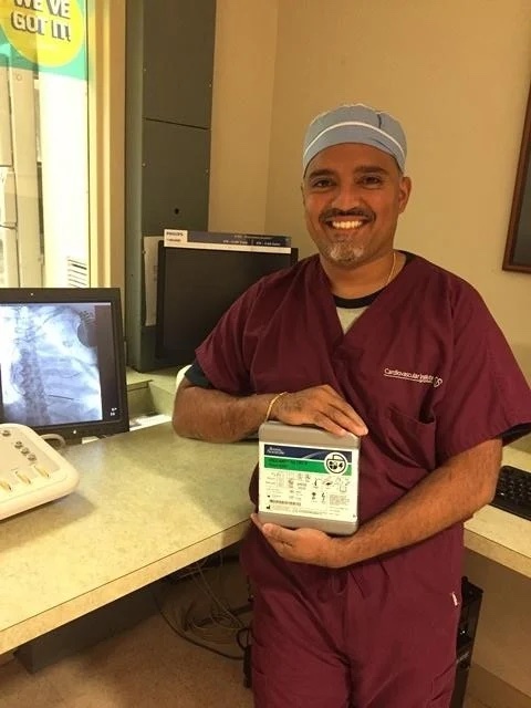 CIS staff member in scrubs smiles while holding a box containing the VIGILANT™ Cardiac Resynchronization Therapy Defibrillator