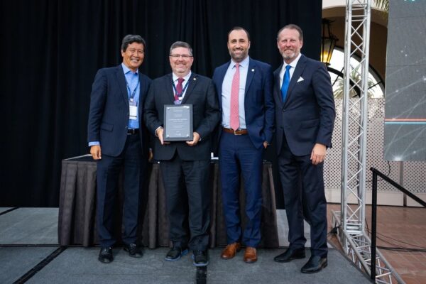 A group of doctors in suits pose with the award for being the #1 telehealth provider for cardiology presented by InTouch Health