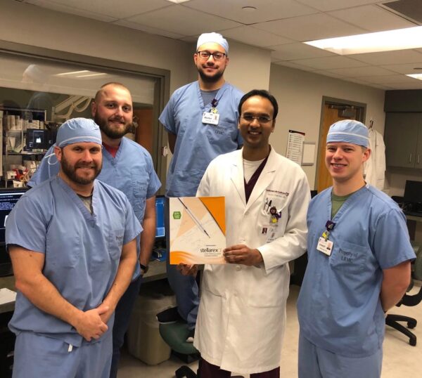 A smiling group of CIS staff members poses with a box containing the Stellarex Drug-Coated Angioplasty Balloon