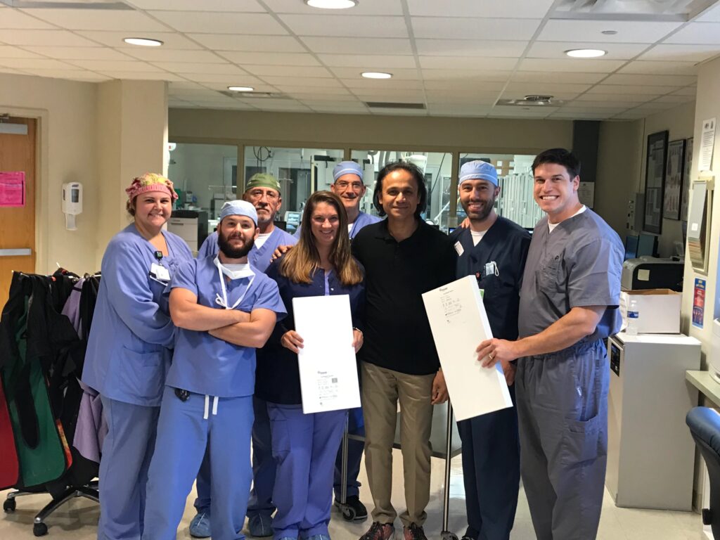 A group of CIS staff posing for a picture with a box containing the ClotTriever Catheter