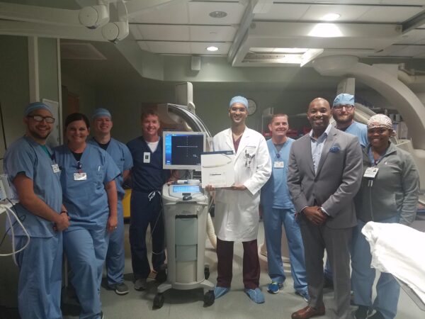 A number of smiling CIS staff members pose with a box containing the OPTICROSS HD IVUS 60 MHz Imaging Catheter