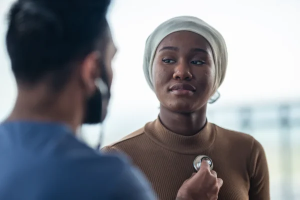 A focused heart doctor conducts a physical examination with a stethoscope on a patient.