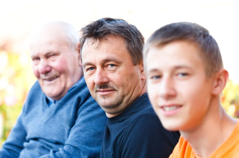 Three generations together: a smiling elderly man, a cardiologist, and a young teenager enjoying a moment side by side.