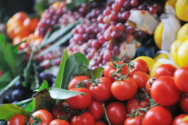 Fresh tomatoes, grapes, and lemons artfully displayed at a vibrant produce market promoting heart health.