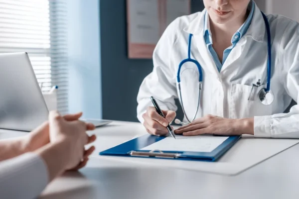 A heart doctor, stethoscope around their neck, attentively jotting down notes on a clipboard during a consultation with a patient at the Cardiovascular Institute of the South.