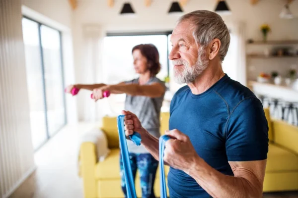 Senior couple staying active and supporting their heart health by doing resistance band exercises together at home.