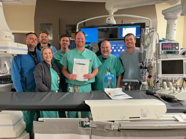 A group of CIS staff in scrubs poses behind an operating table with a package containing Abbott medical equipment