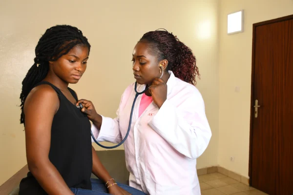 A cardiologist using a stethoscope to listen to a patient's heart in a medical office.