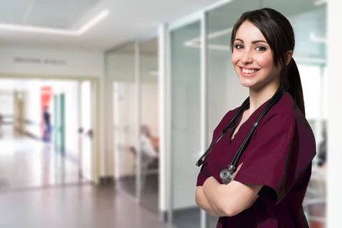 A confident cardiologist with a stethoscope smiling in a hospital corridor.