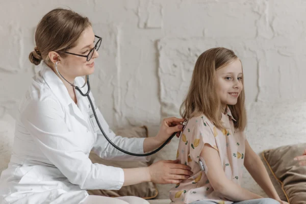 A healthcare professional using a stethoscope to listen to a young patient's back during a medical check-up at the Cardiovascular Institute of the South.