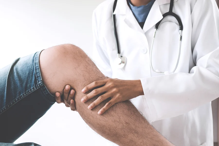 A healthcare professional examining a patient's knee, possibly assessing for injury or pain related to cardiovascular health at the Cardiovascular Institute of the South.