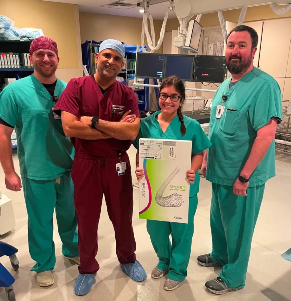 A small group of CIS staff poses with a box containing the Radianz Smart Stent