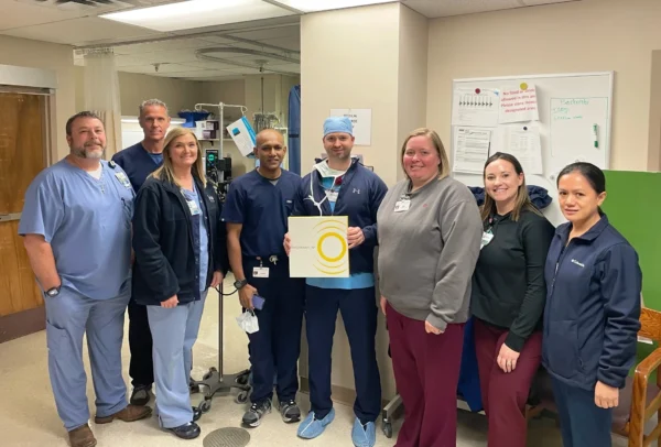 A group of CIS staff in scrubs posing with a box containing the Shockwave lithotripsy balloon system