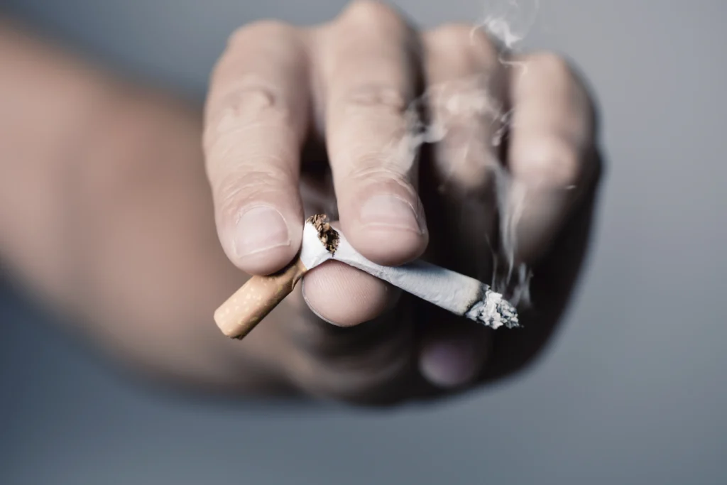 A hand snapping a cigarette in half, signifying a decision to quit smoking for better heart health.